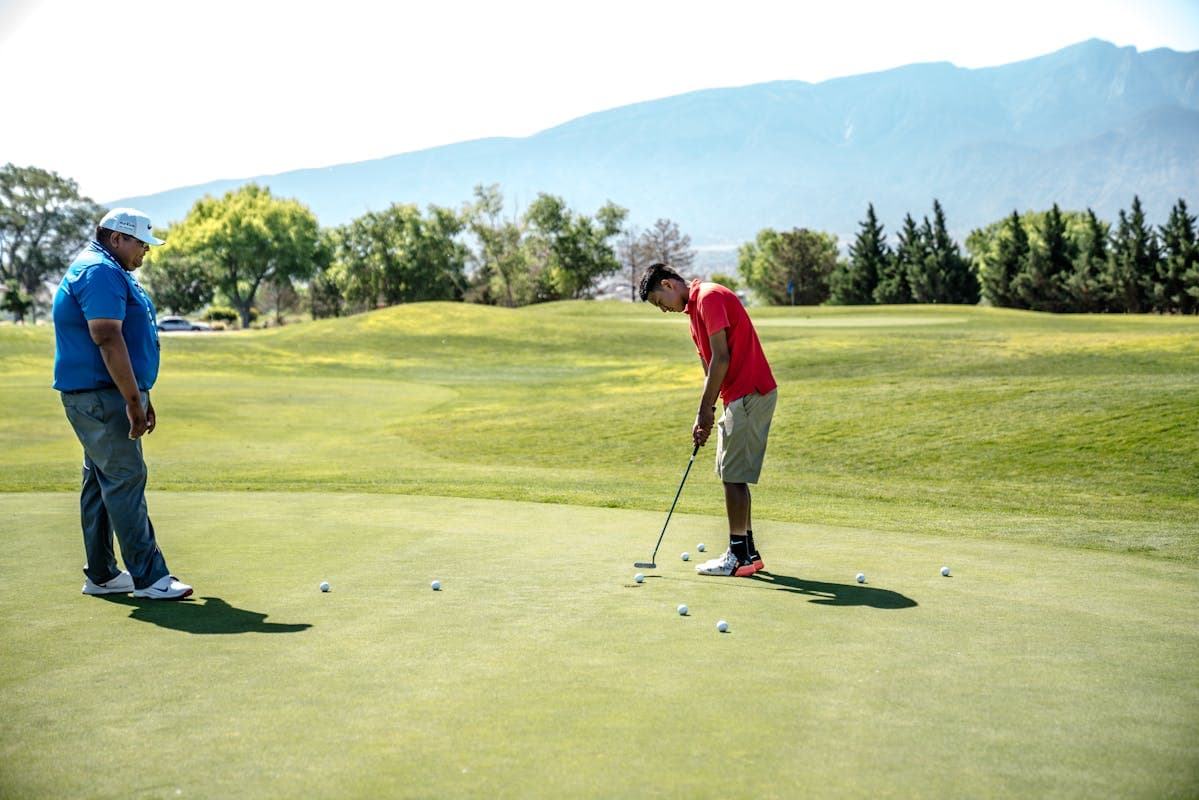 Golf instructor watching student putt on the green